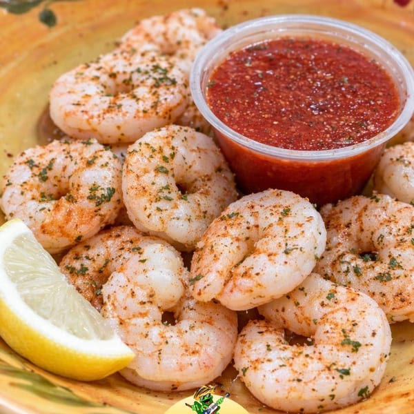 Tony Locos' seasoned shrimp with a lemon wedge and a side of red dipping sauce.